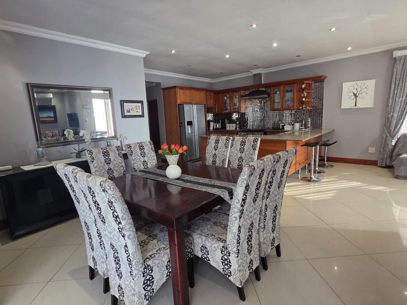 Spacious open-plan living and dining area featuring a well-appointed kitchen with granite countertops, mosaic backsplash, and modern tiled flooring throughout.