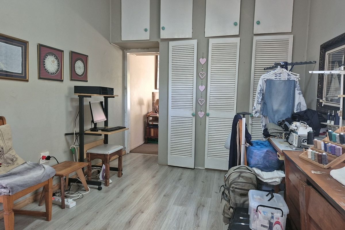 A bedroom featuring laminate flooring and extensive built-in storage with louvered doors, offering functional space for a home office or hobby area.