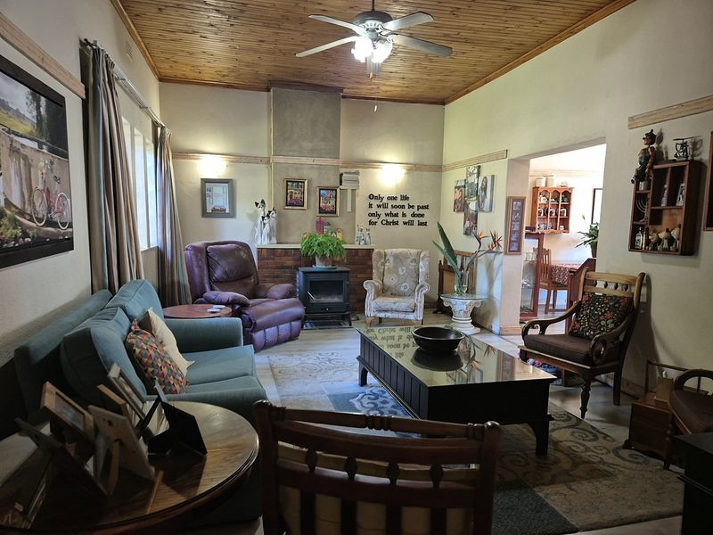 A cozy living room featuring a wood-paneled ceiling, a brick fireplace with a wood-burning stove, and wall sconce lighting.