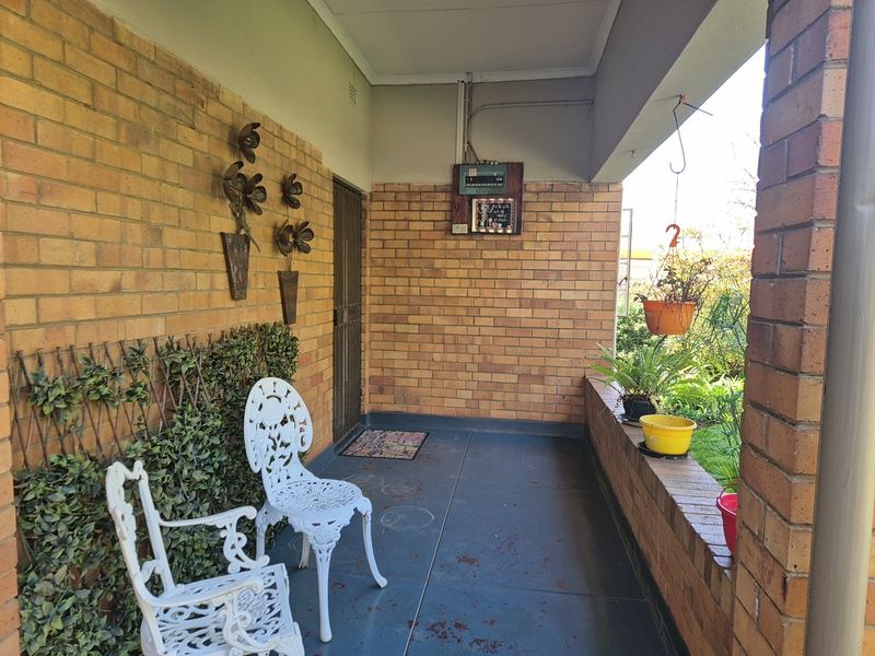 A covered patio area featuring exposed brick walls, a brick balustrade, and concrete flooring, providing a functional outdoor space.