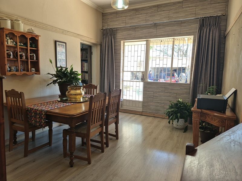 A dining room featuring laminate flooring, decorative wall paneling, and a security gate leading to the exterior.