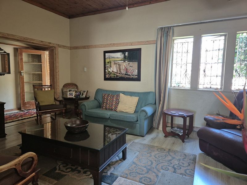 A living room featuring a timber ceiling, laminate flooring, and windows fitted with security bars, offering a traditional and functional living space.