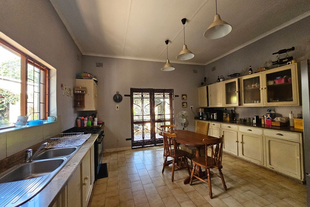 Spacious kitchen featuring built-in cabinetry, double basin sink, tiled flooring, and direct access to the outdoor area through a security gate.