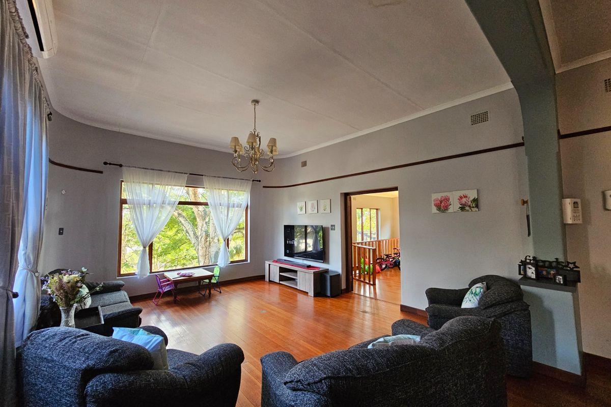 Spacious living room featuring polished hardwood floors, a large picture window with natural light, and classic coved ceilings.