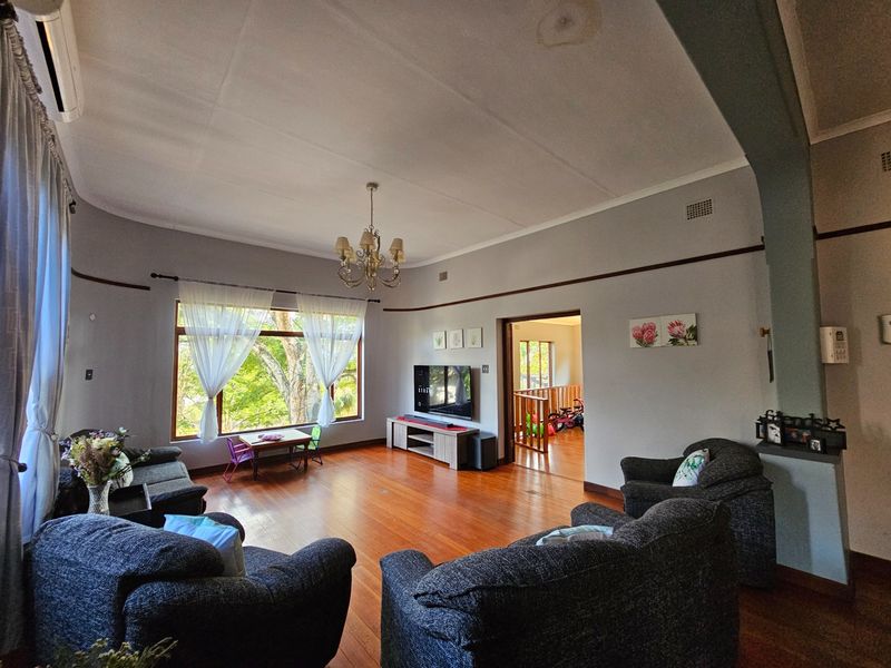 Spacious living room featuring polished hardwood floors, a large picture window with natural light, and classic coved ceilings.