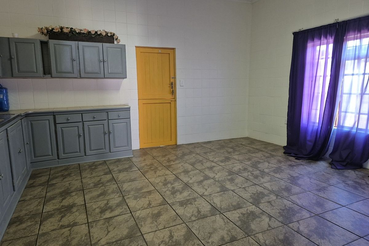A functional kitchen space featuring built-in cabinetry, tiled flooring, and tiled wall finishes, offering a blank canvas for potential updates.