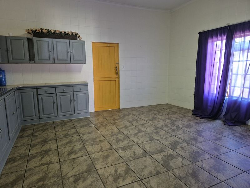 A functional kitchen space featuring built-in cabinetry, tiled flooring, and tiled wall finishes, offering a blank canvas for potential updates.