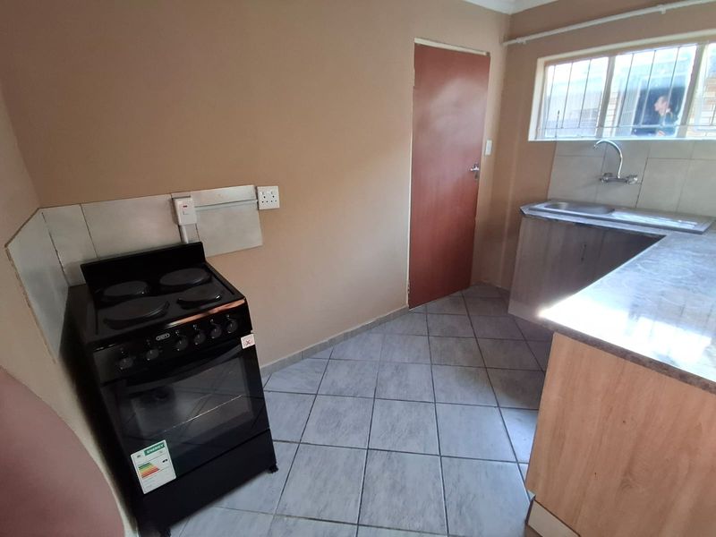 A functional kitchen featuring tiled flooring, built-in stove, and stainless steel sink, offering a blank canvas for potential cosmetic updates and modern finishes.