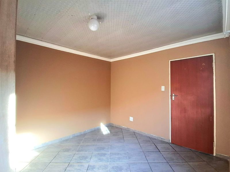 An empty bedroom featuring tiled flooring, coved ceilings, and a neutral wall finish, providing a blank canvas for personalization.