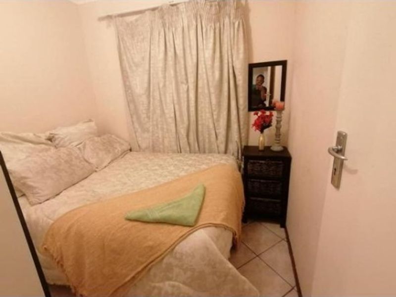 A compact bedroom featuring tiled flooring and neutral wall finishes, providing a functional sleeping space.