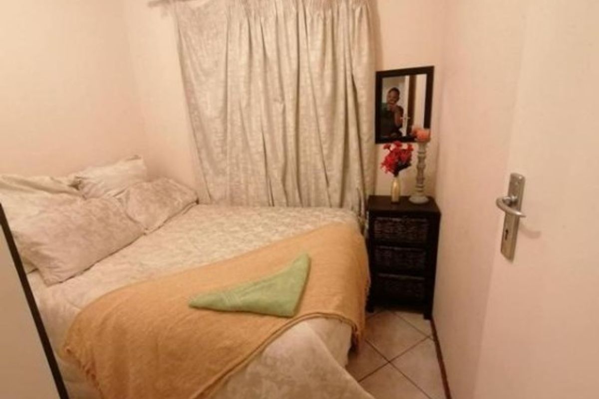 A compact bedroom featuring tiled flooring and neutral wall finishes, providing a functional sleeping space.