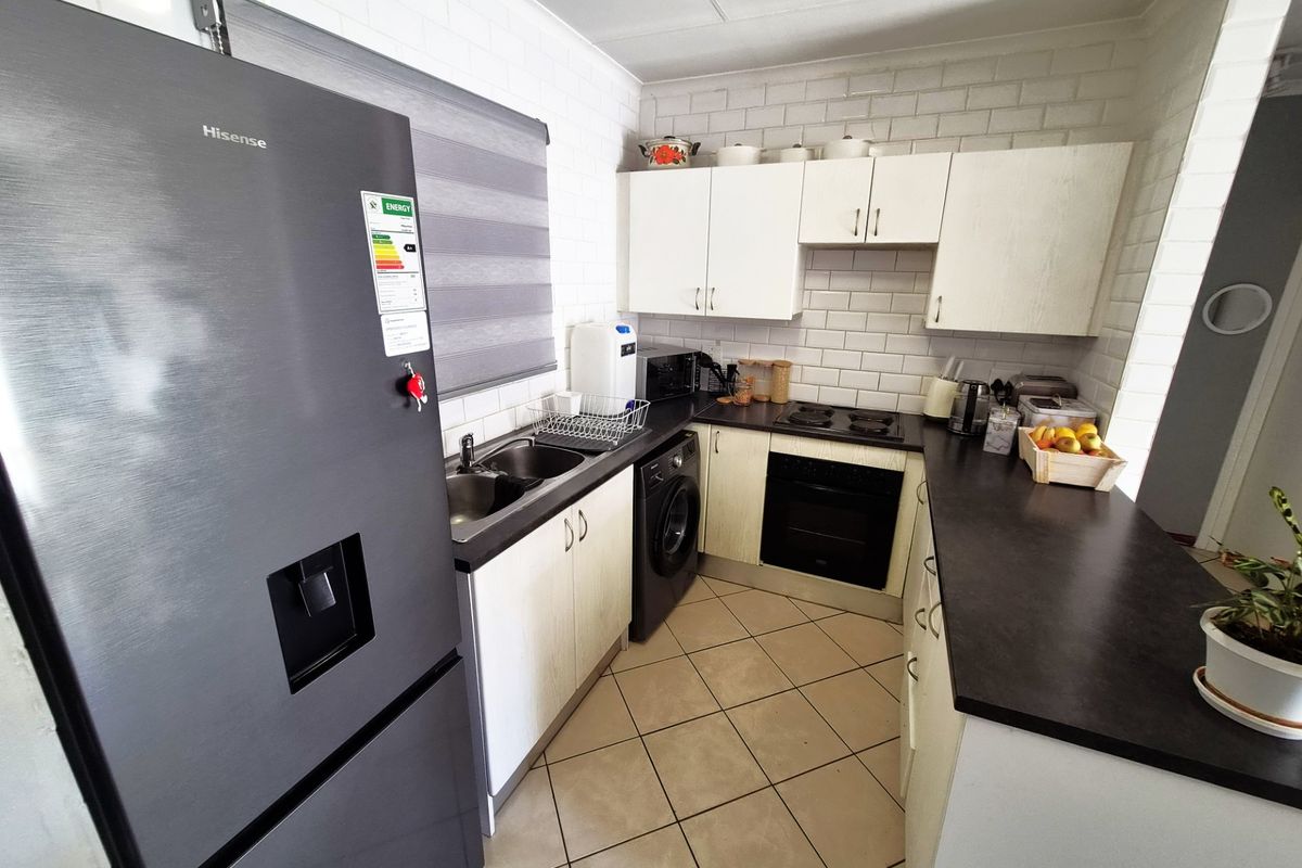A functional kitchen featuring white cabinetry, dark laminate countertops, tiled backsplash, built-in oven, electric hob, and tiled flooring.