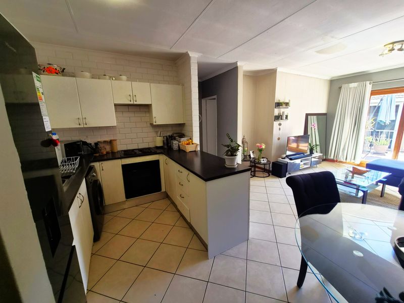 Open-plan kitchen and living area featuring tiled flooring, modern cabinetry, built-in oven, and direct access to a balcony through a sliding glass door.
