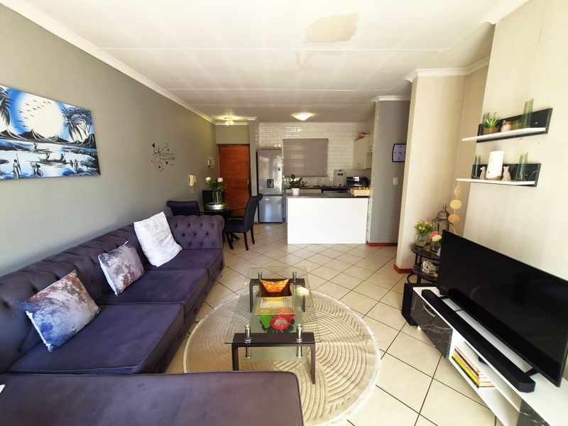 Open-plan living area featuring tiled flooring and a functional kitchen with a breakfast island and subway tile backsplash.