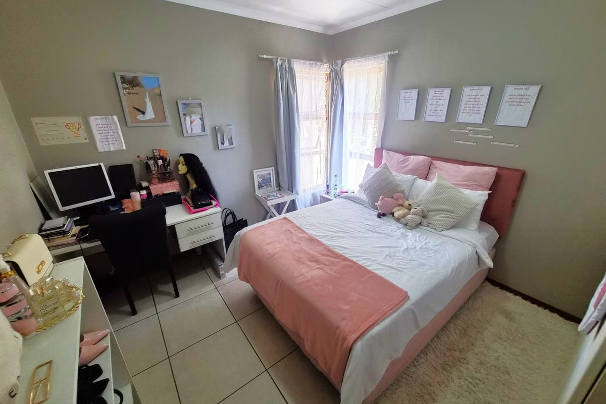 A functional bedroom featuring tiled flooring and neutral wall tones, offering a comfortable space with natural light from the corner window.