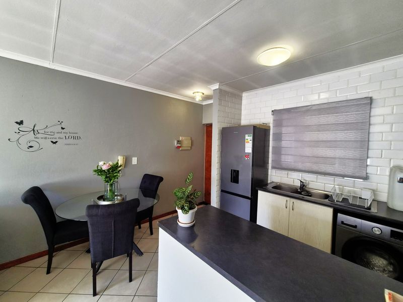 Open plan kitchen and dining area featuring subway tile backsplash, laminate countertops, and tiled flooring, creating a functional and connected living space.