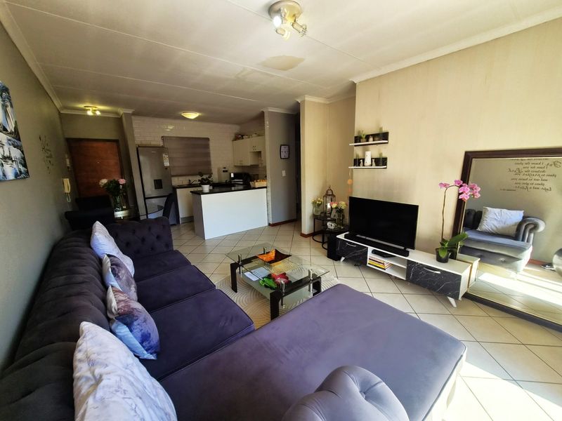 Open plan living area featuring tiled flooring and a functional kitchen with built-in cabinetry and a central island.