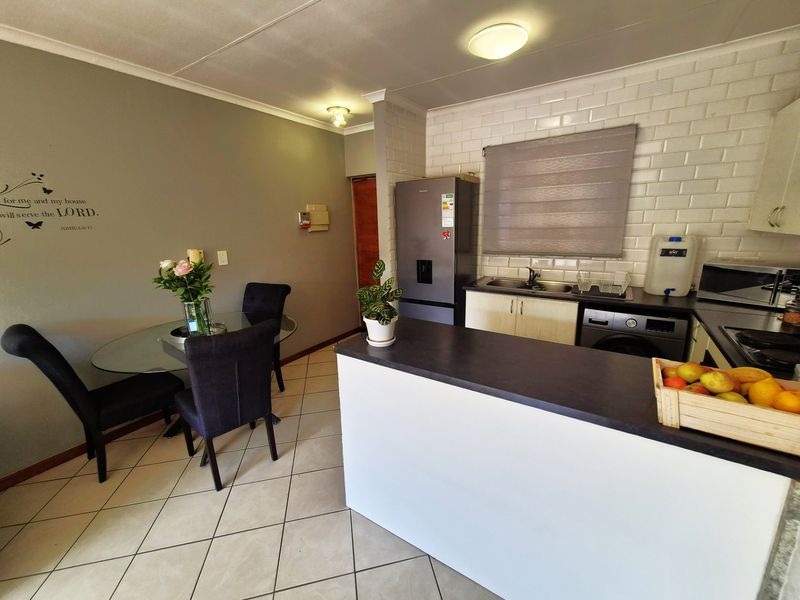 Open plan kitchen and dining area featuring subway tile backsplash, laminate countertops, and neutral ceramic floor tiles.