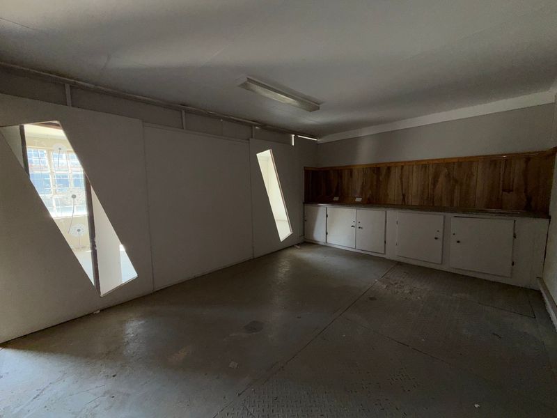 A functional utility space featuring built-in cabinetry, wood paneling, and concrete flooring, suitable for storage or workshop use.
