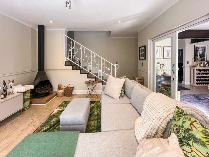 A well-maintained living room featuring a modern freestanding fireplace, a decorative wrought iron staircase balustrade, and sliding glass doors leading to an adjacent space.
