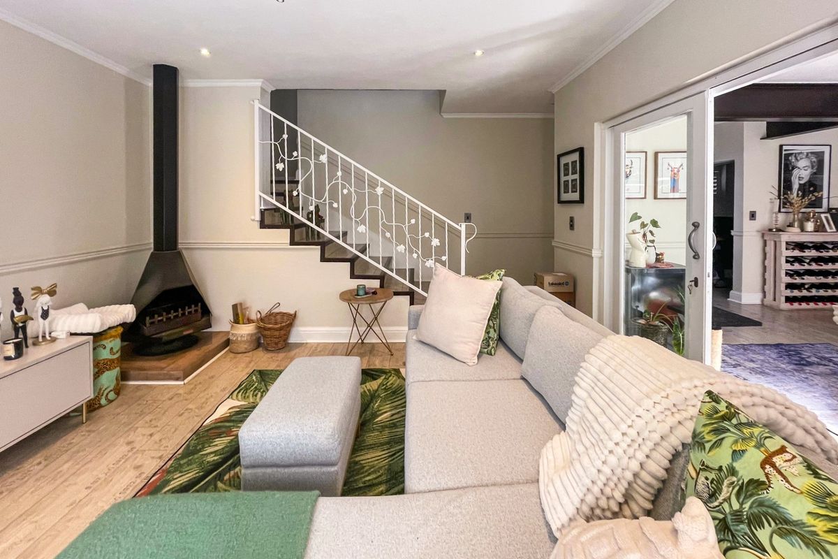 A well-maintained living room featuring a modern freestanding fireplace, a decorative wrought iron staircase balustrade, and sliding glass doors leading to an adjacent space.