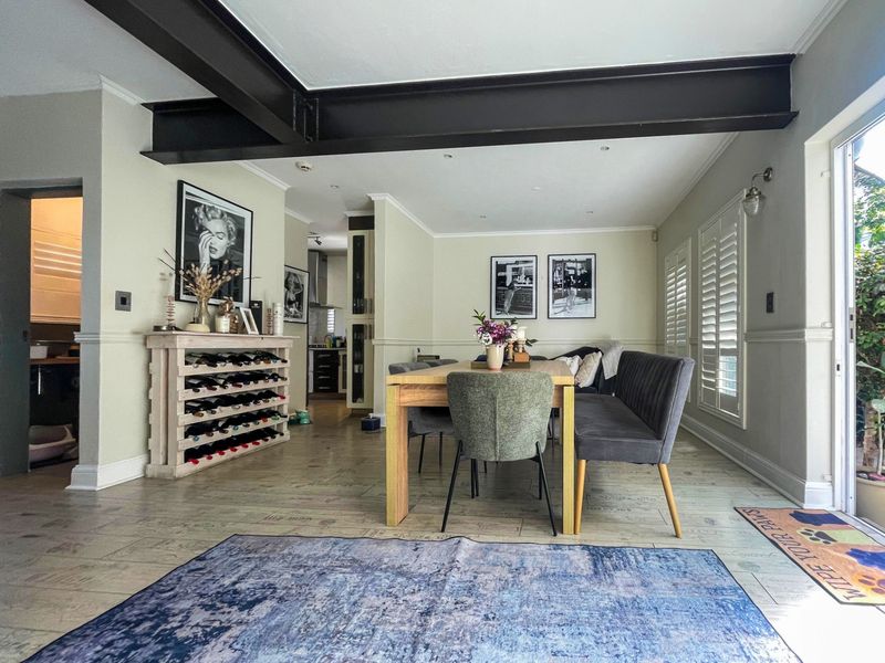 Open-plan dining area featuring an exposed structural steel beam, laminate flooring, wainscoting, and sliding glass doors leading to the exterior.