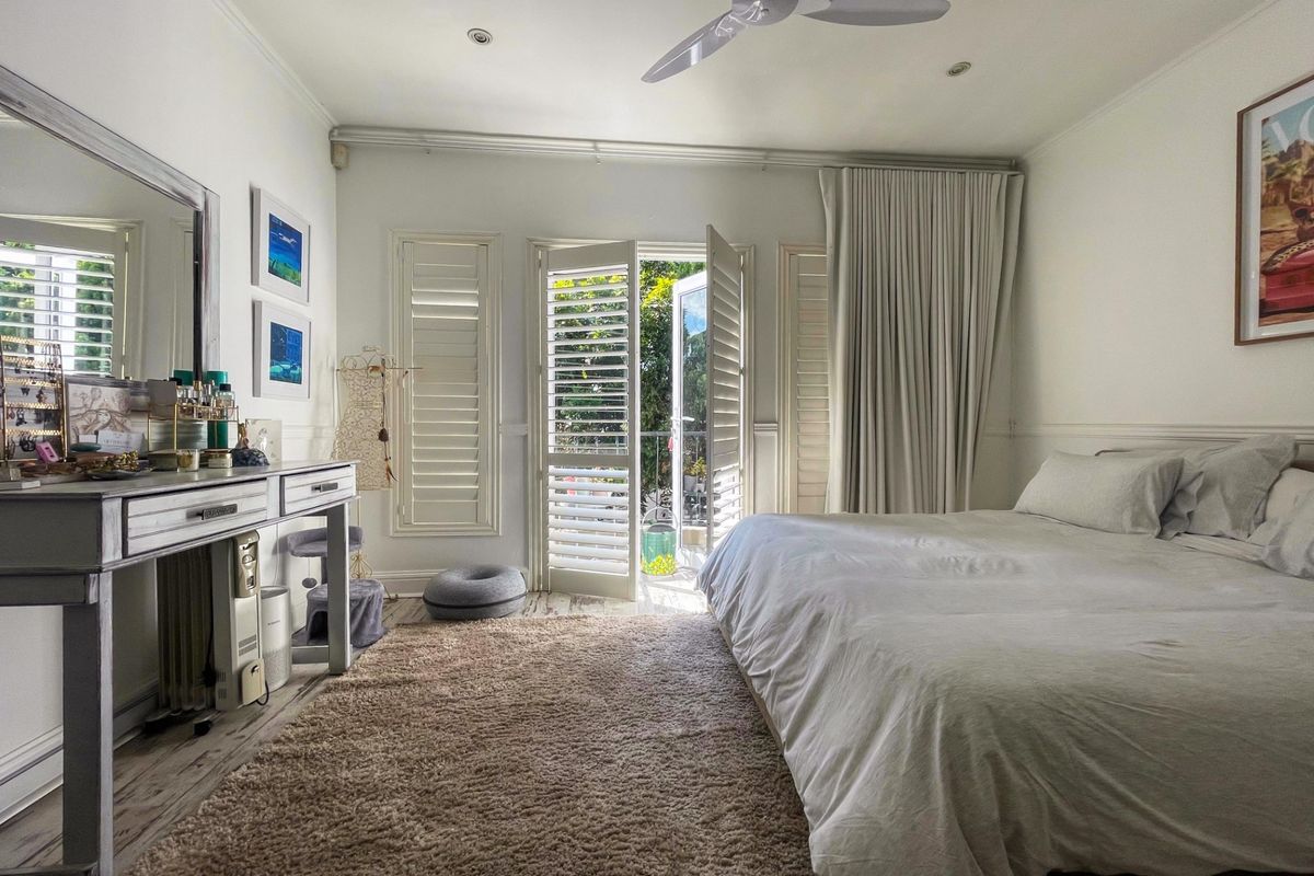 A bright bedroom featuring laminate flooring, recessed lighting, a ceiling fan, and plantation shutters with direct access to an outdoor area through french doors.