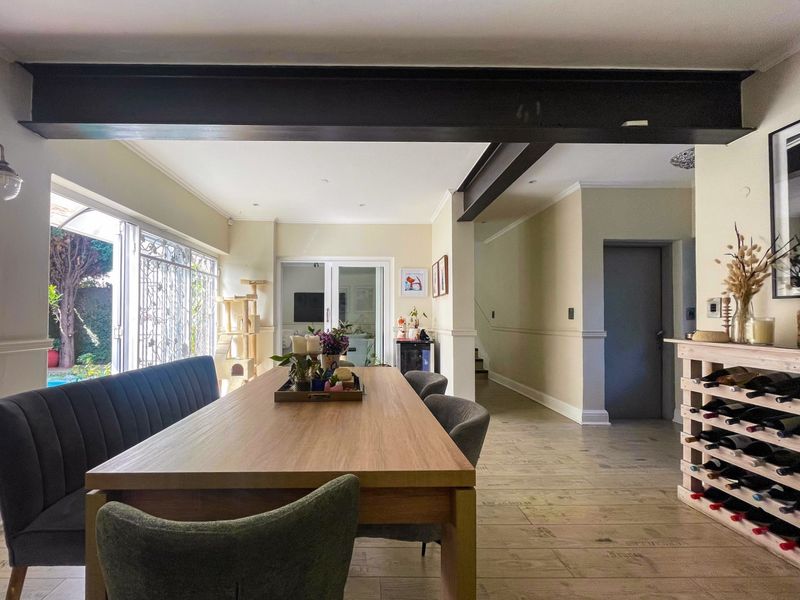Spacious dining area featuring tiled flooring, exposed structural steel beams, and large sliding glass doors providing access to the garden.