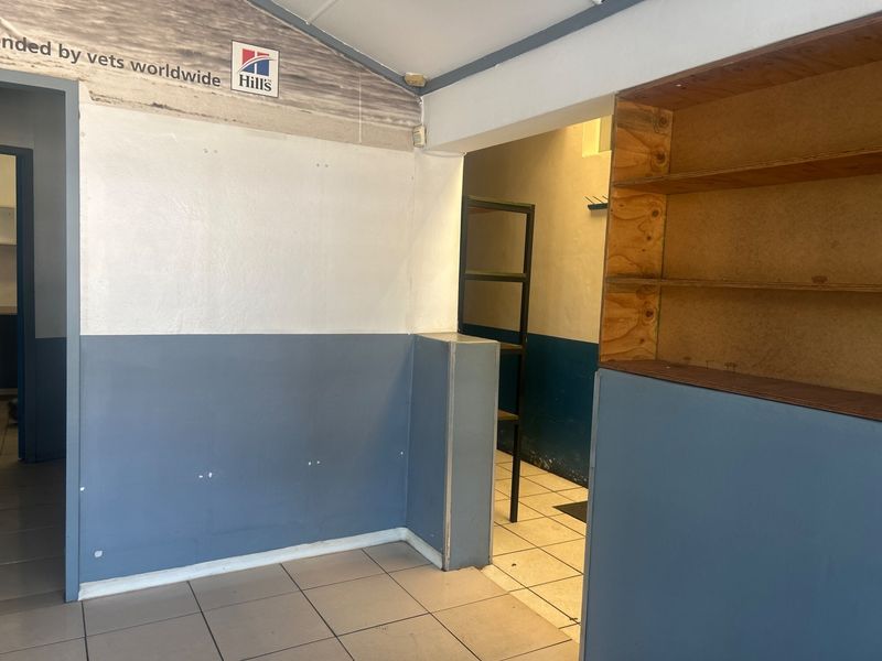 An empty office space featuring tiled flooring and built-in plywood shelving, requiring cosmetic updates to improve the overall aesthetic.