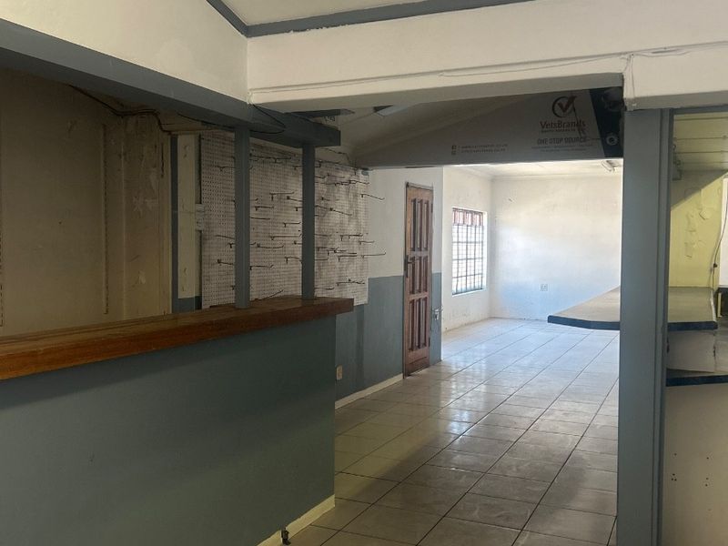 An open-plan office space featuring tiled flooring, a built-in service counter, and a pegboard display wall, offering a functional layout for business operations.