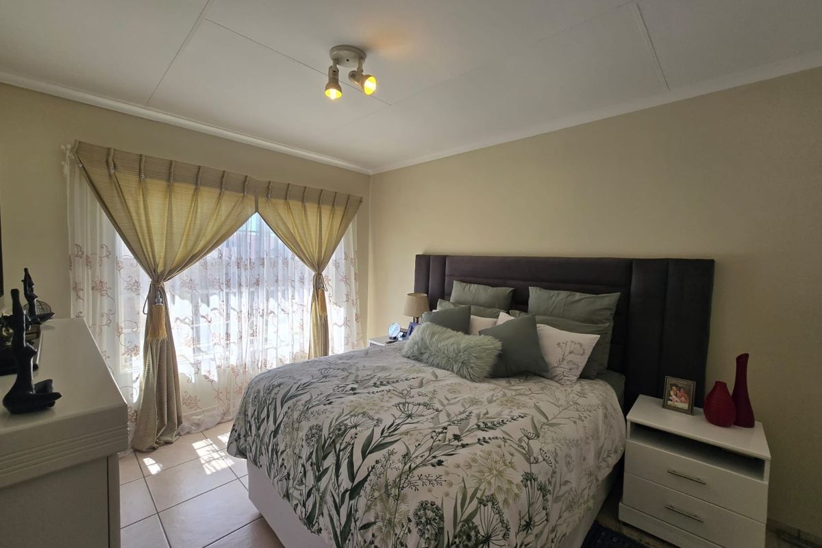 A well-lit bedroom featuring tiled flooring and a neutral color palette, providing a comfortable and functional sleeping space.