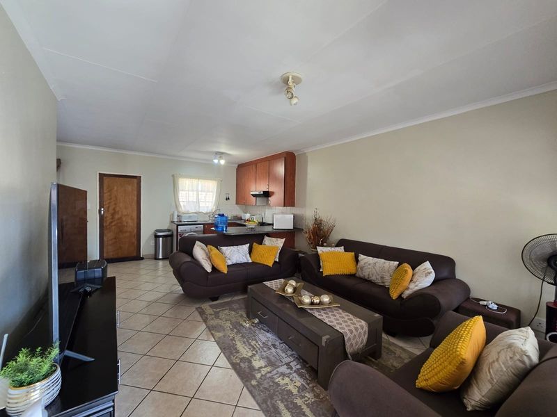 Open-plan living area featuring tiled flooring and a functional kitchen with built-in cabinetry and a breakfast counter.