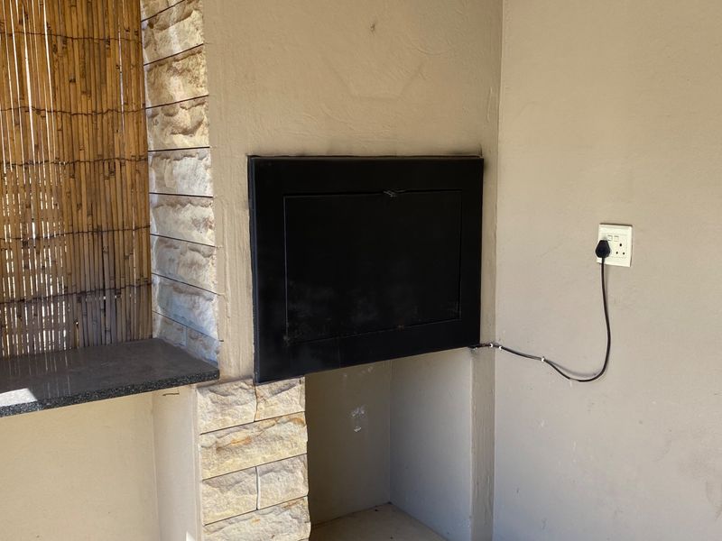 Outdoor patio area featuring a built-in braai with stone cladding and a granite countertop surface.