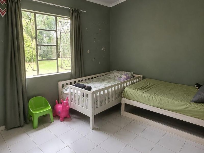 A bedroom featuring tiled flooring, a steel-framed window, and a ceiling vent, currently showing signs of wall surface wear.
