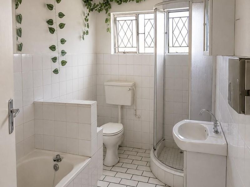 A functional bathroom featuring a tiled bathtub, corner shower enclosure, pedestal basin, and toilet with classic white wall and floor tiling.