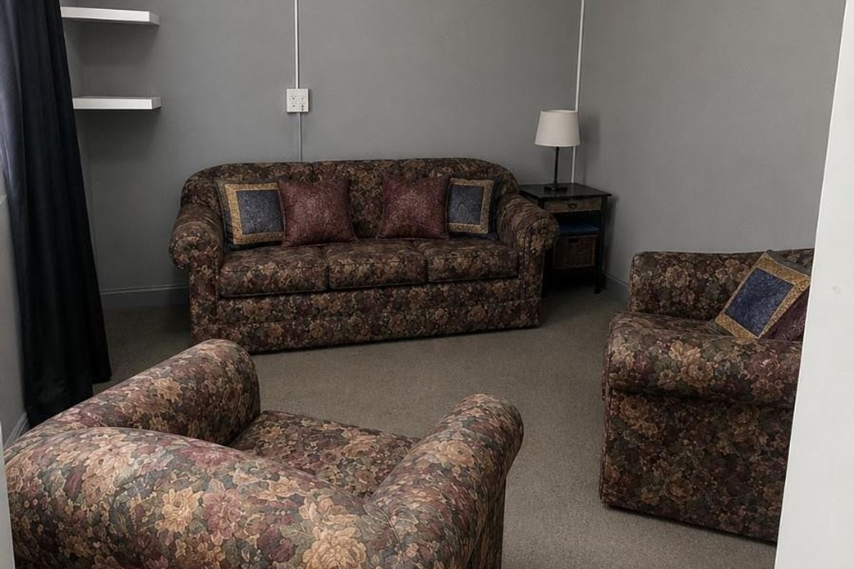 A living room featuring grey walls, carpeted flooring, and built-in floating wall shelves.