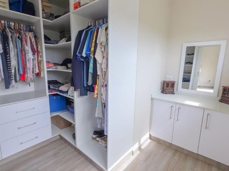 A well-organized bedroom featuring extensive built-in cupboard storage and a dedicated vanity area with integrated cabinetry and laminate flooring.