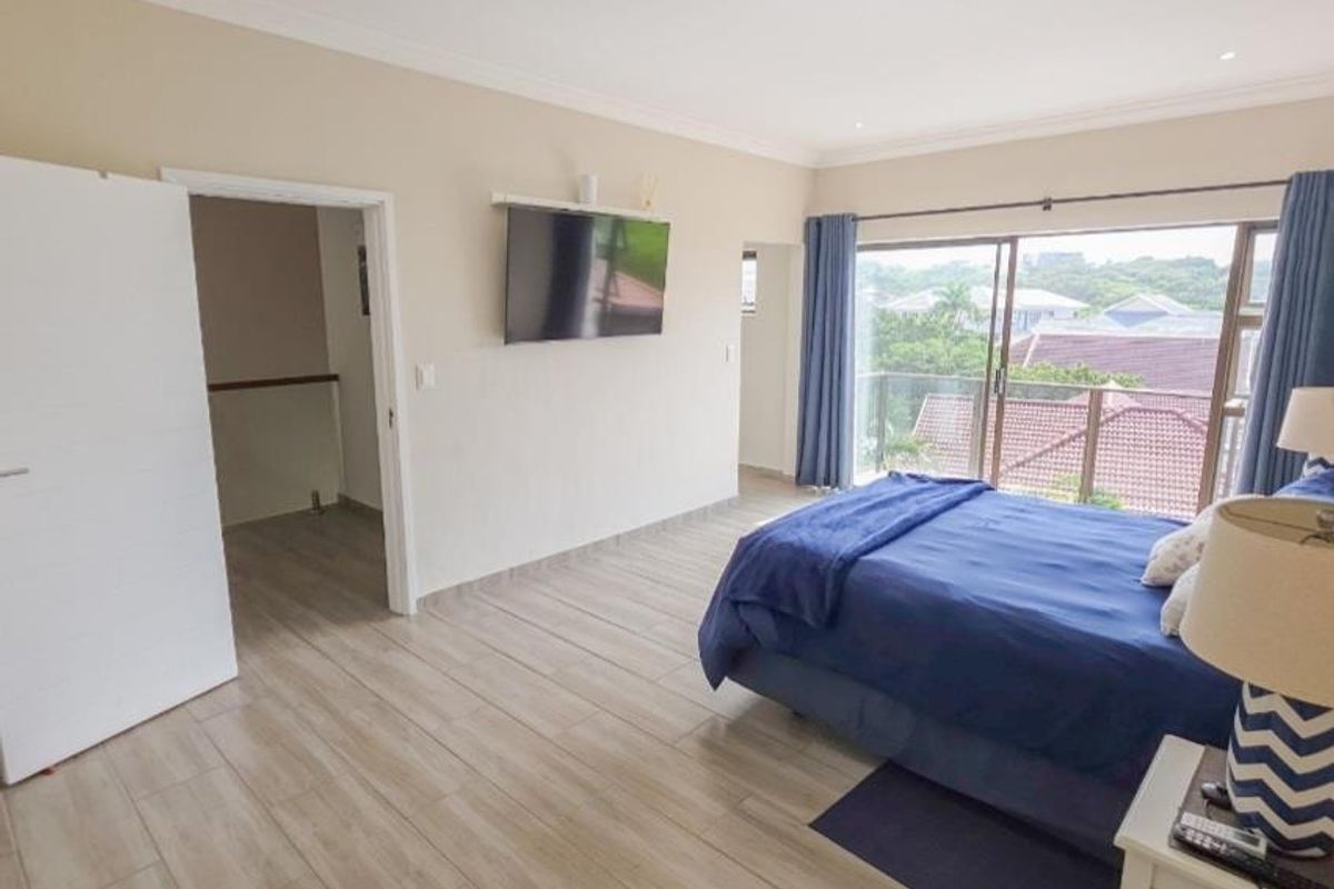 Spacious bedroom featuring tiled flooring, recessed lighting, and a sliding glass door leading to a balcony with scenic views.