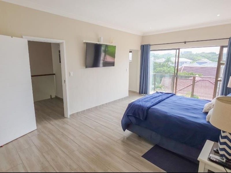 Spacious bedroom featuring tiled flooring, recessed lighting, and a sliding glass door leading to a balcony with scenic views.