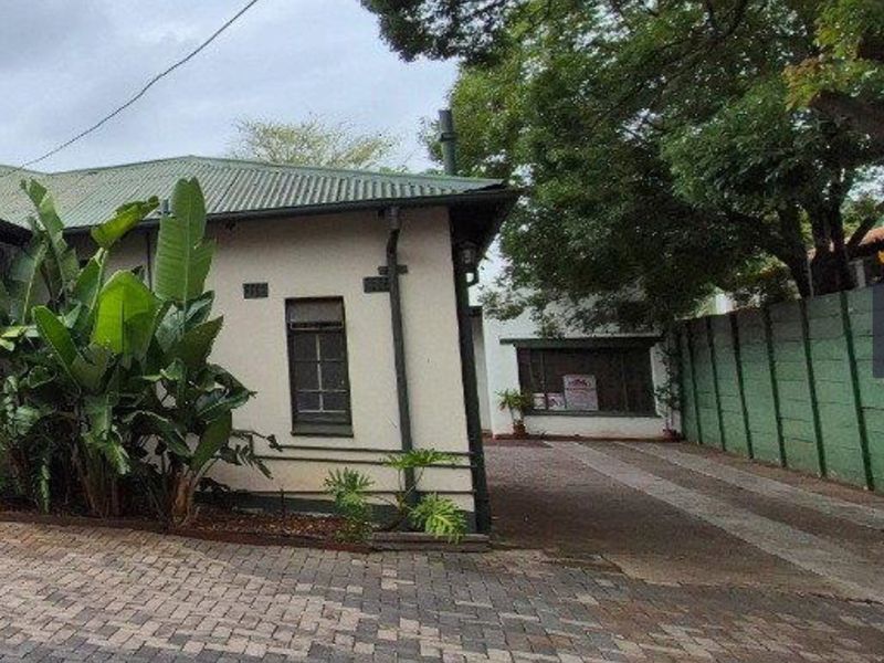 Front exterior view of the property featuring a paved driveway, corrugated metal roofing, and established boundary walling.