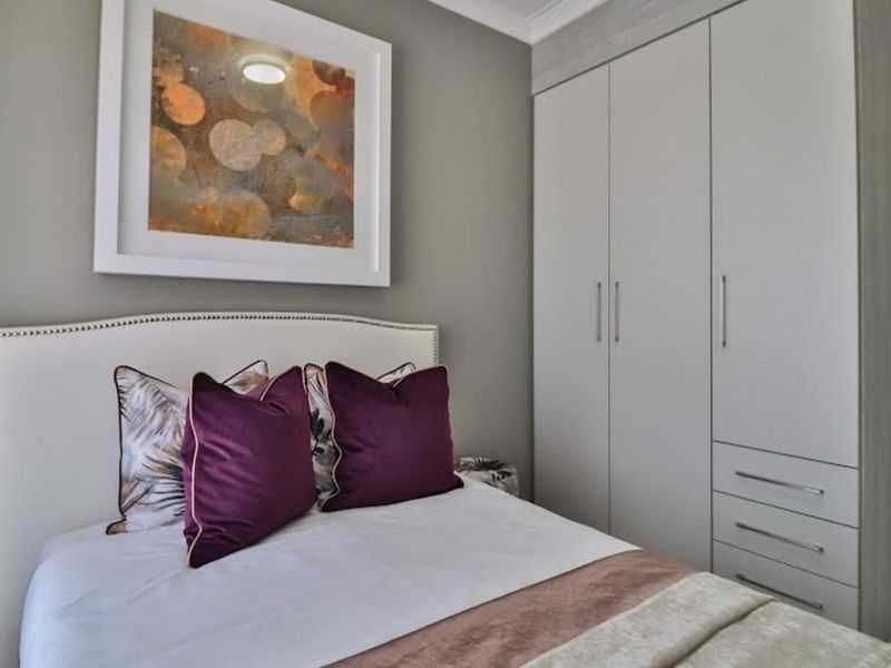 A well-maintained bedroom featuring neutral wall tones, built-in cabinetry with integrated drawers, and decorative coving.
