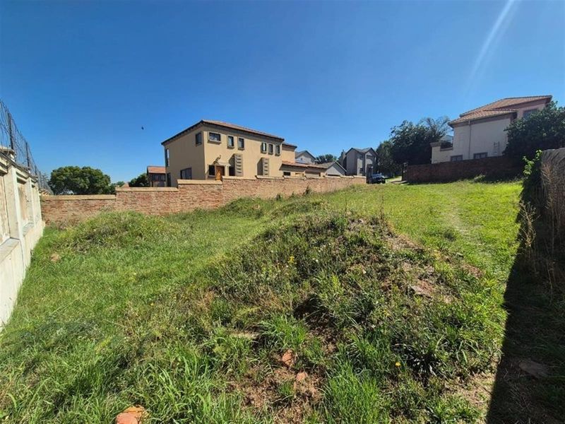 An undeveloped residential garden area featuring uneven terrain and brick boundary walls, offering potential for landscaping and outdoor development.