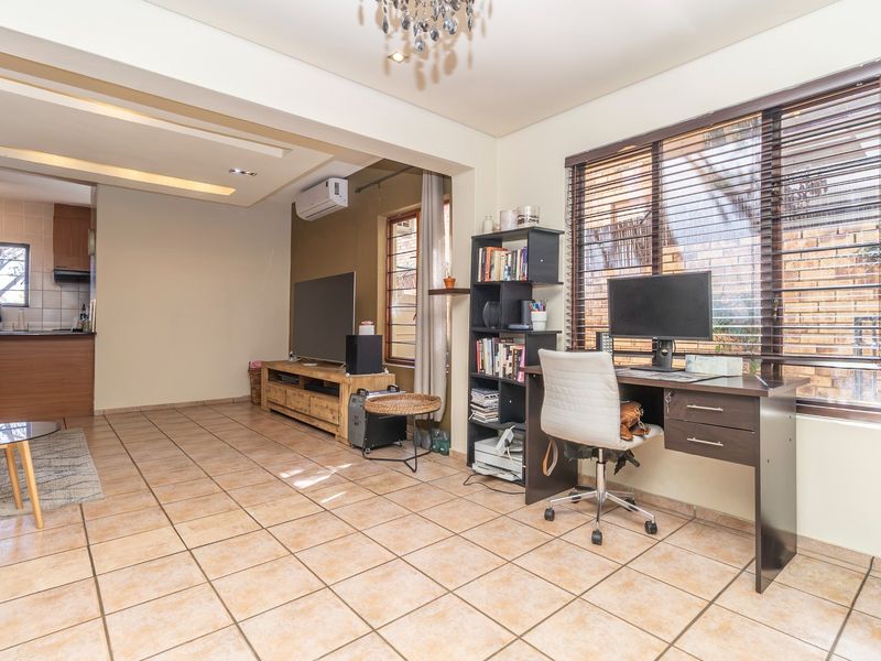Open-plan living area featuring tiled flooring, recessed ceiling lighting, and an integrated kitchen space with neutral wall finishes and large windows.