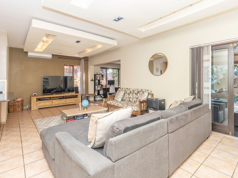 Spacious open-plan living area featuring tiled floors, a recessed ceiling with downlights, and direct access to the outdoor patio through a sliding glass door.