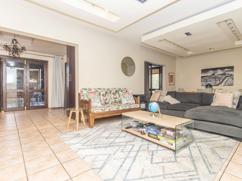 Spacious living room featuring tiled flooring, recessed ceiling with downlights, and double glass doors leading to an outdoor area.