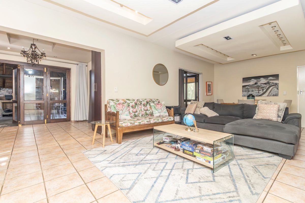 Spacious living room featuring tiled flooring, recessed ceiling with downlights, and double glass doors leading to an outdoor area.