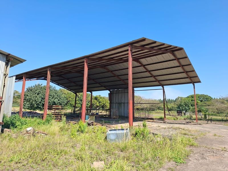 Open-sided industrial utility structure featuring a steel frame and corrugated metal roof, situated on a concrete slab with surrounding grounds.