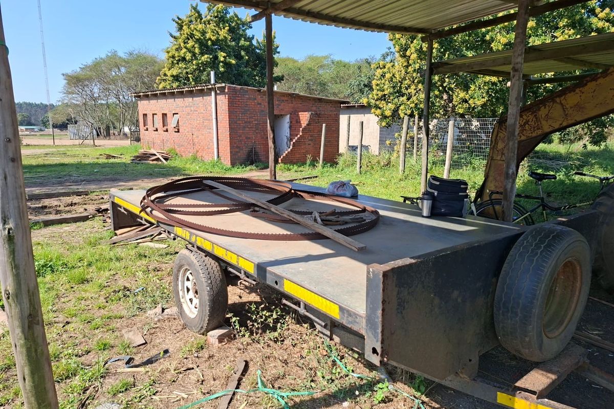 Outdoor area featuring a covered structure and a detached brick outbuilding in need of maintenance.