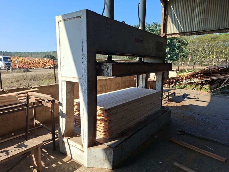 Industrial workspace featuring a heavy-duty hydraulic press machine situated in an open-sided commercial facility with concrete flooring.