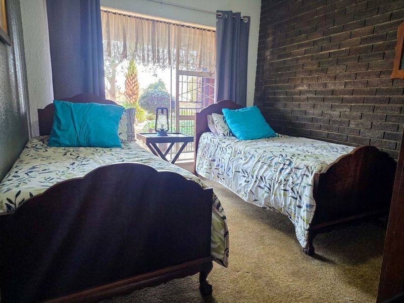 A bedroom featuring an exposed brick feature wall, carpeted flooring, and a sliding glass door providing access to the outdoor area.